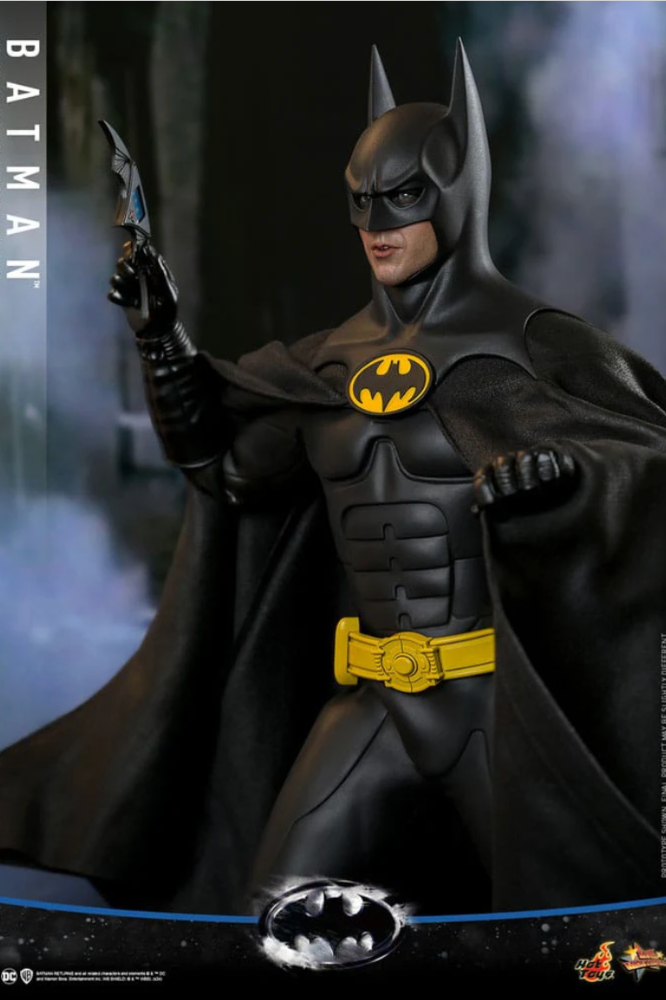 Figura de Batman 1/6 escala Hot Toys con traje negro y fondo urbano.