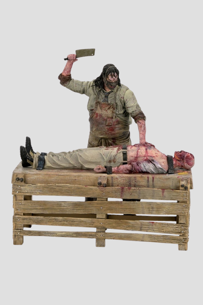 Diorama Slaughterhouse de Leatherface de NECA, perteneciente a La Matanza de Texas: El Origen, con figura de 18 cm, víctima sobre mesa de madera y accesorios de matadero.