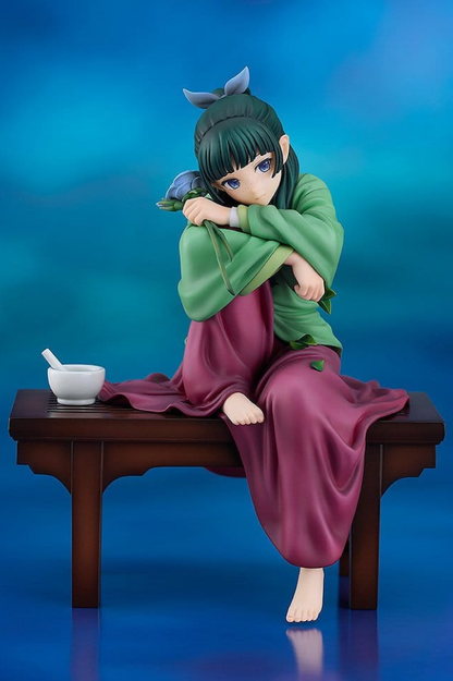 Figura de Maomao de The Apothecary Diaries de Good Smile Company, colección G.S. Collection a escala 1/7 y 18 cm, sentada con vestimenta verde y morada y una flor azul.